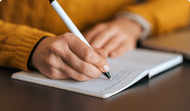 Close up of hands writing in a notebook