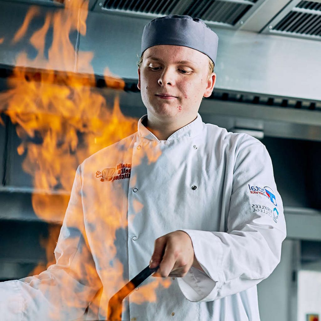 A young male student chef cooking with fire