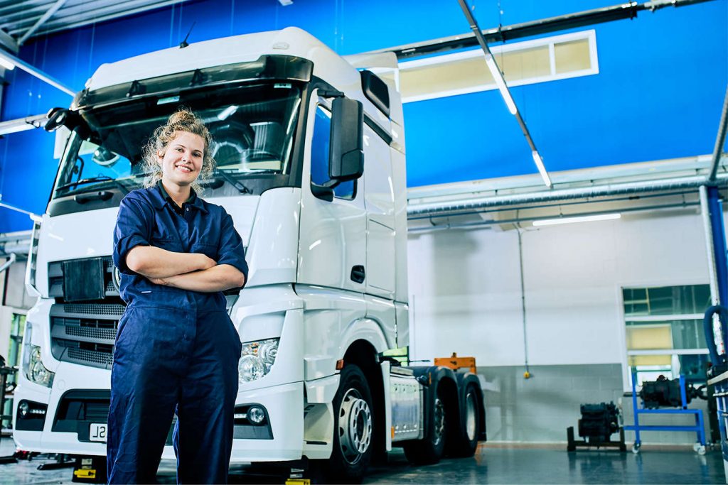 a female kirklees student wearing blue overalls stood in front of a truck