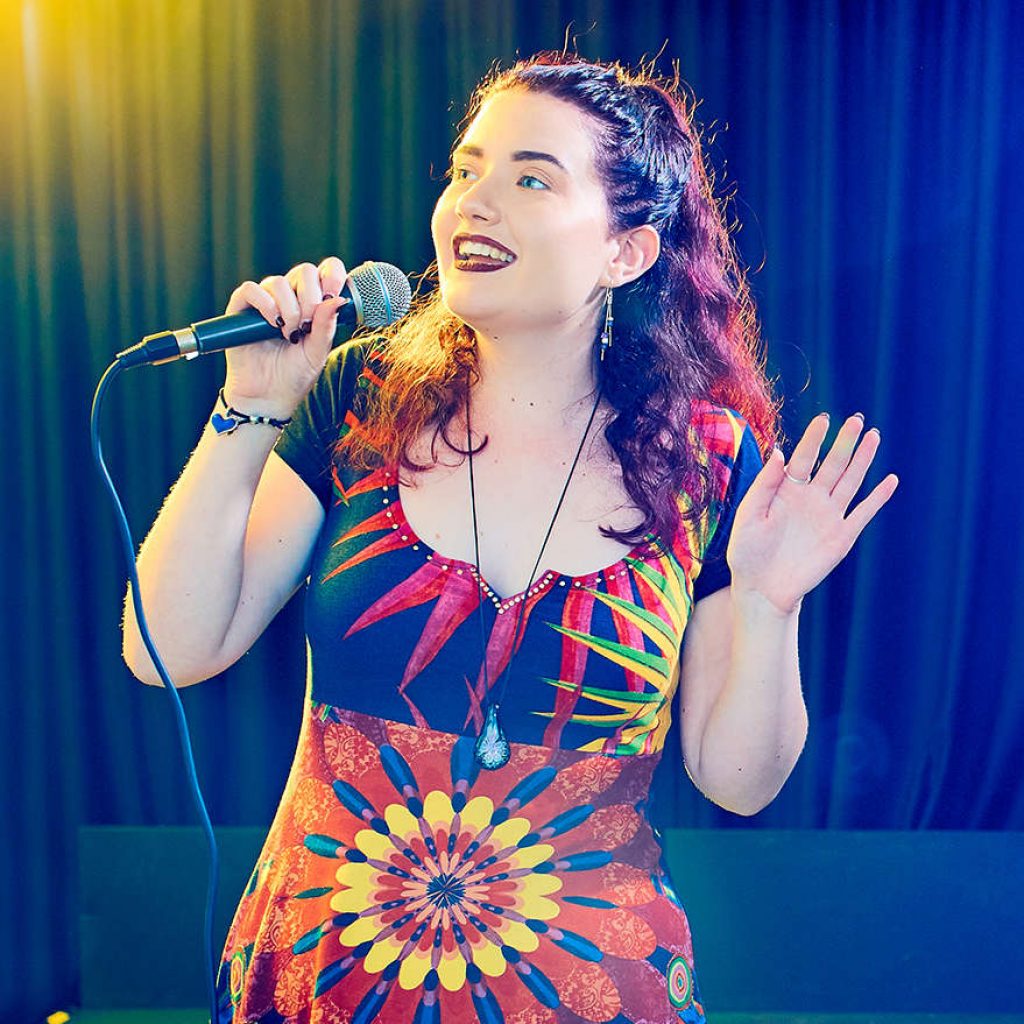 A young female stood singing with a microphone