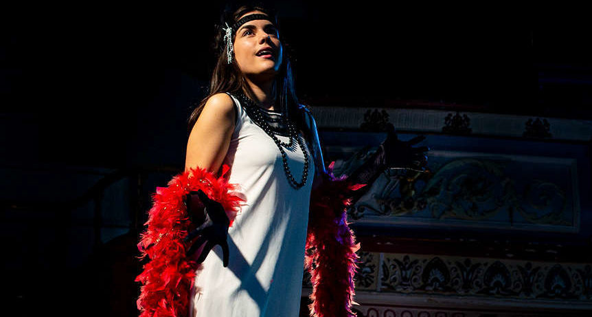 A young female performer stood on stage gazing off camera