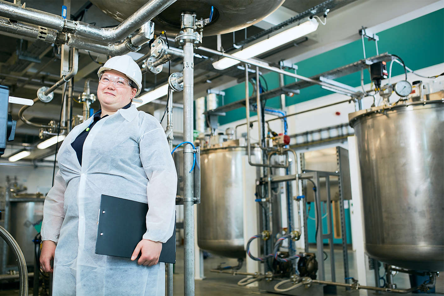 a lady stood in front of complex manufacturing machinery