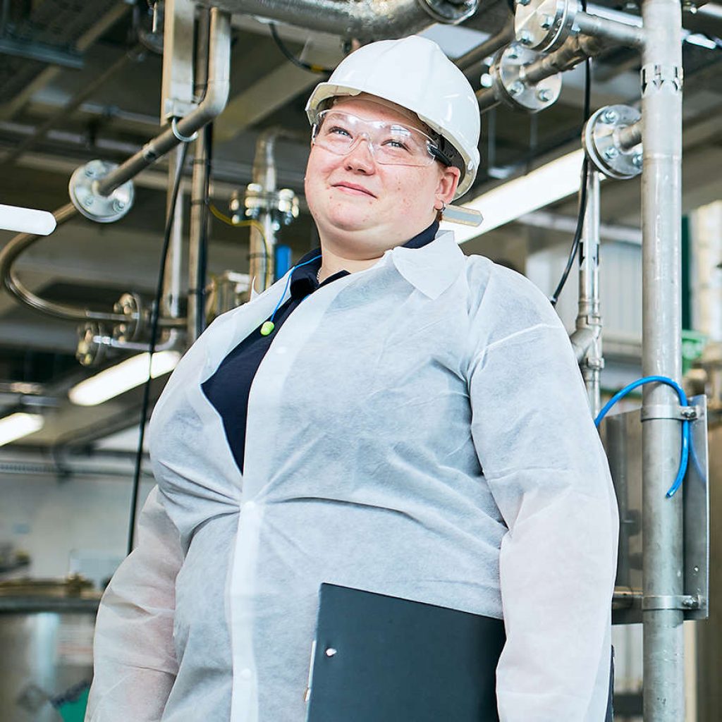 Female engineering student stood in front of manufacturing machinery