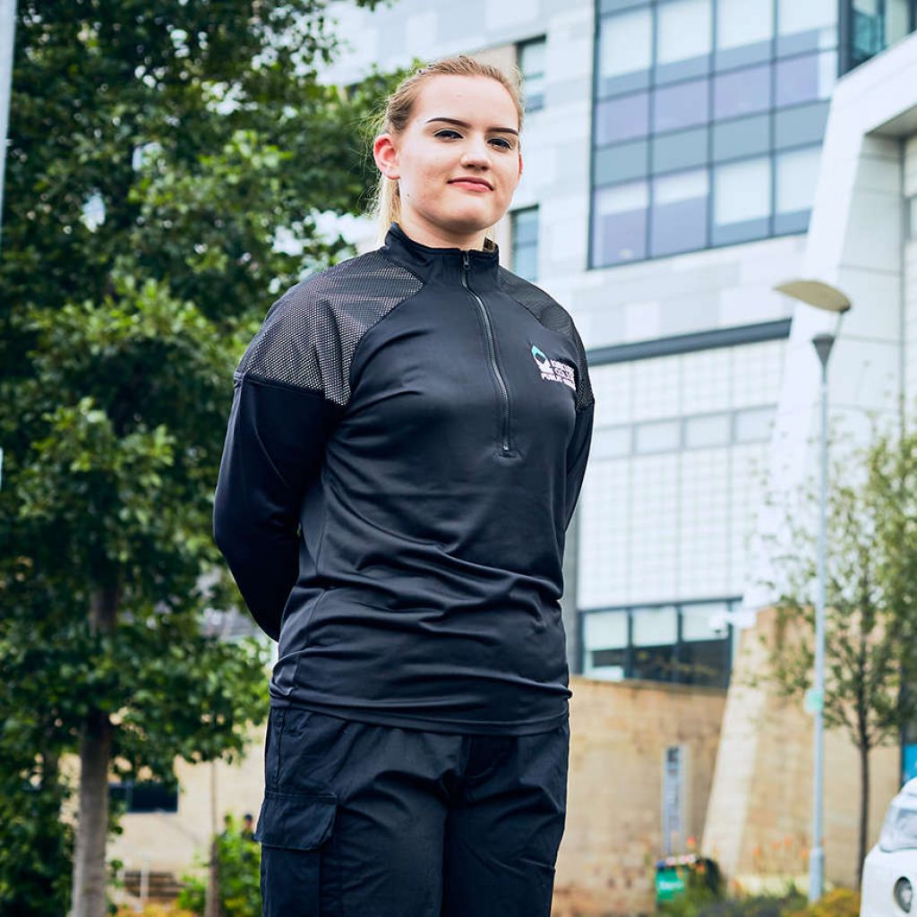 A young girl wearing a kirklees college uniform stood in front of a police car outside the Huddersfield Centre Campus