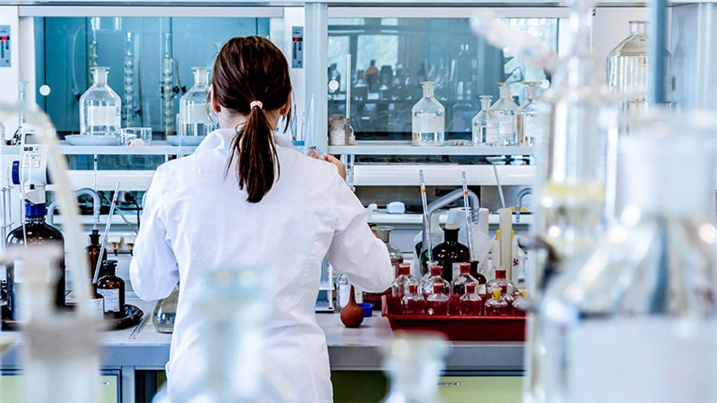 A young female scientist with her back to the camera working in the lab