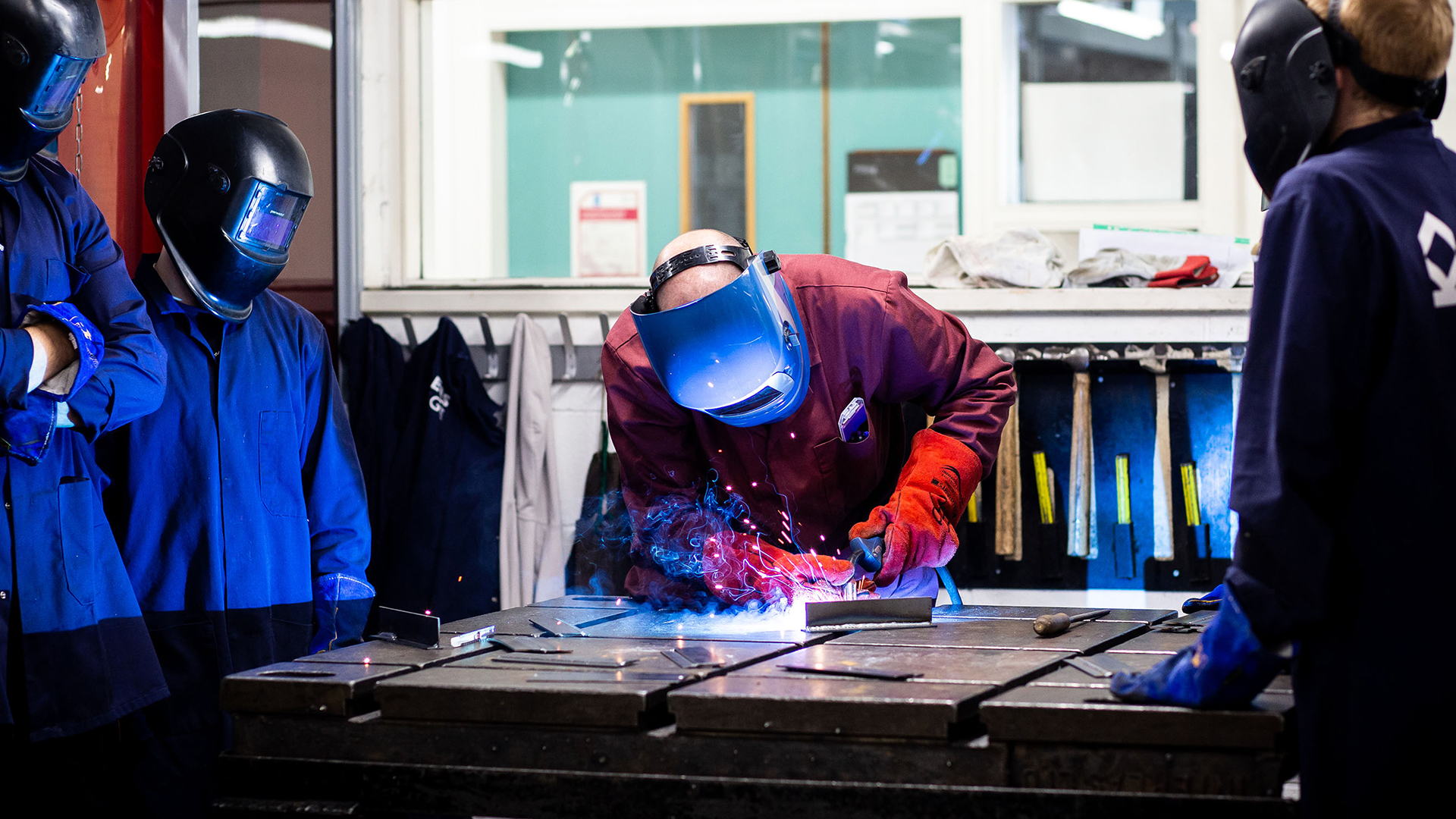 A group of students watching a tutor show them how to weld