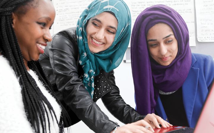 Two female students in headscarves chatting with a female tutor