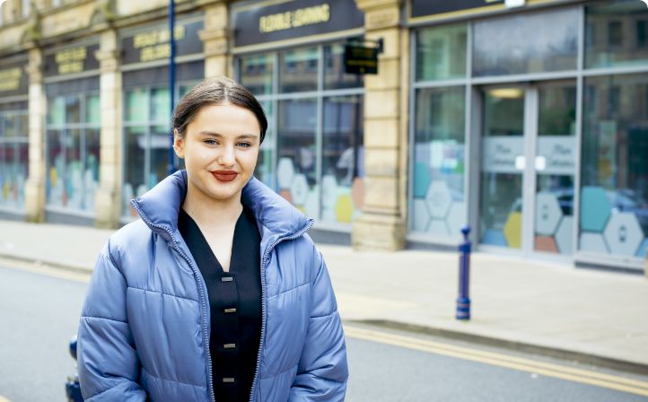 Female apprentice stood outside a campus building