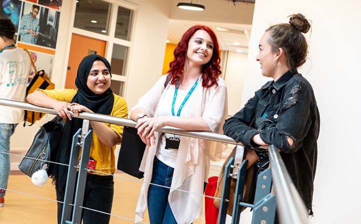 Three female student chatting in a college campus