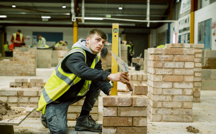 Male student practising his bricklaying skills on a mock brick wall
