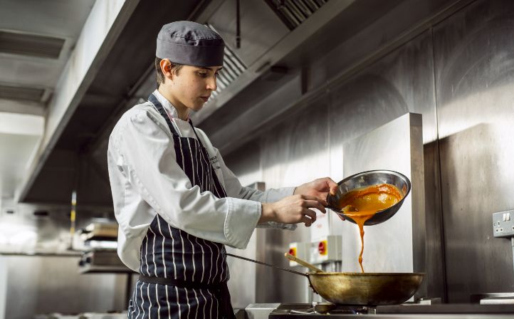 A male student cooking in the college restaurant