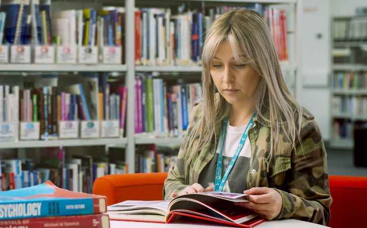 Mature female student working through a textbook in the library