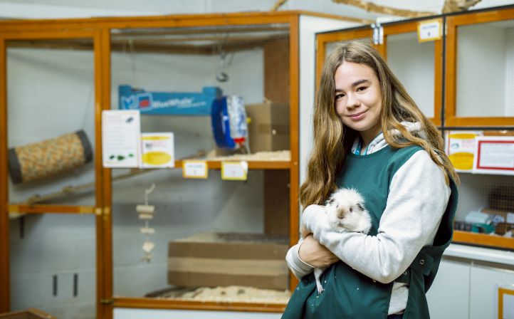 Female student holding a guinea pig in the animal care centre
