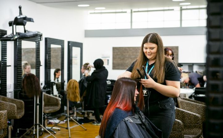 Female student straightening a ladies hair in the college salon