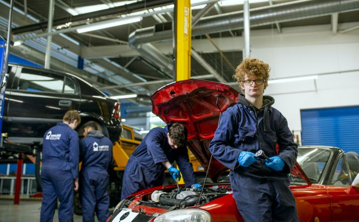 Young mechanic leaning on bonnet of a car