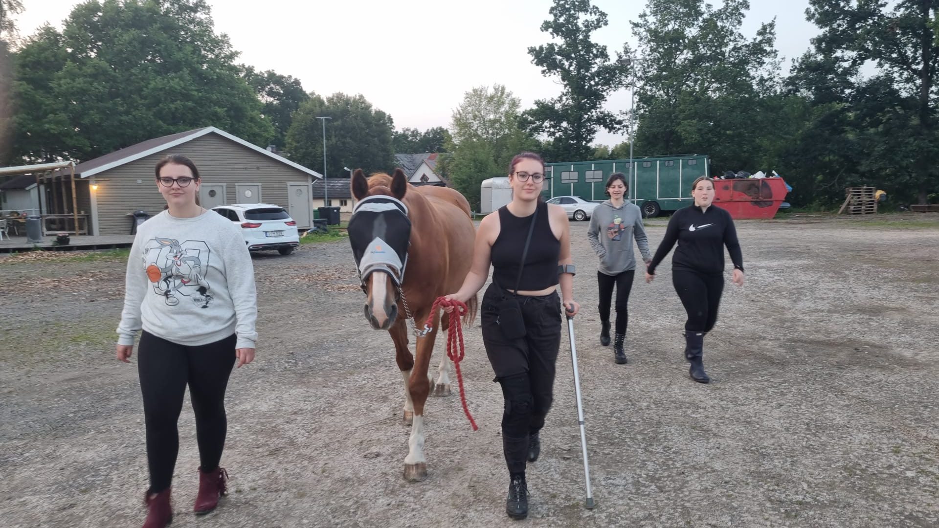 Students walk alongside and guide a horse through camp site in Sweden