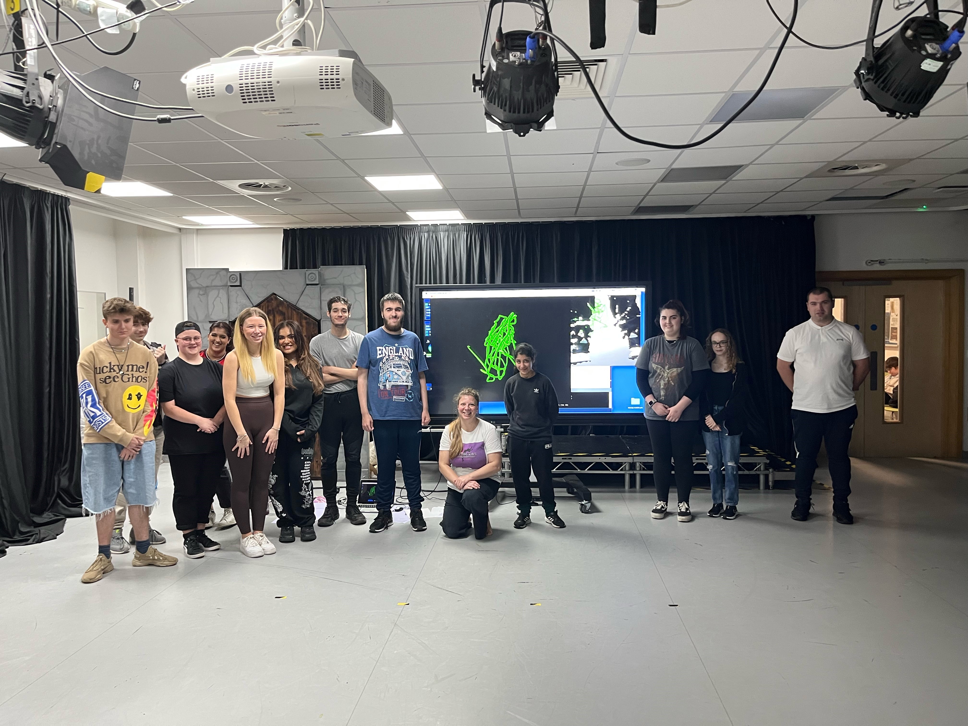 Students standing in workshop next to projector showing their sculptures