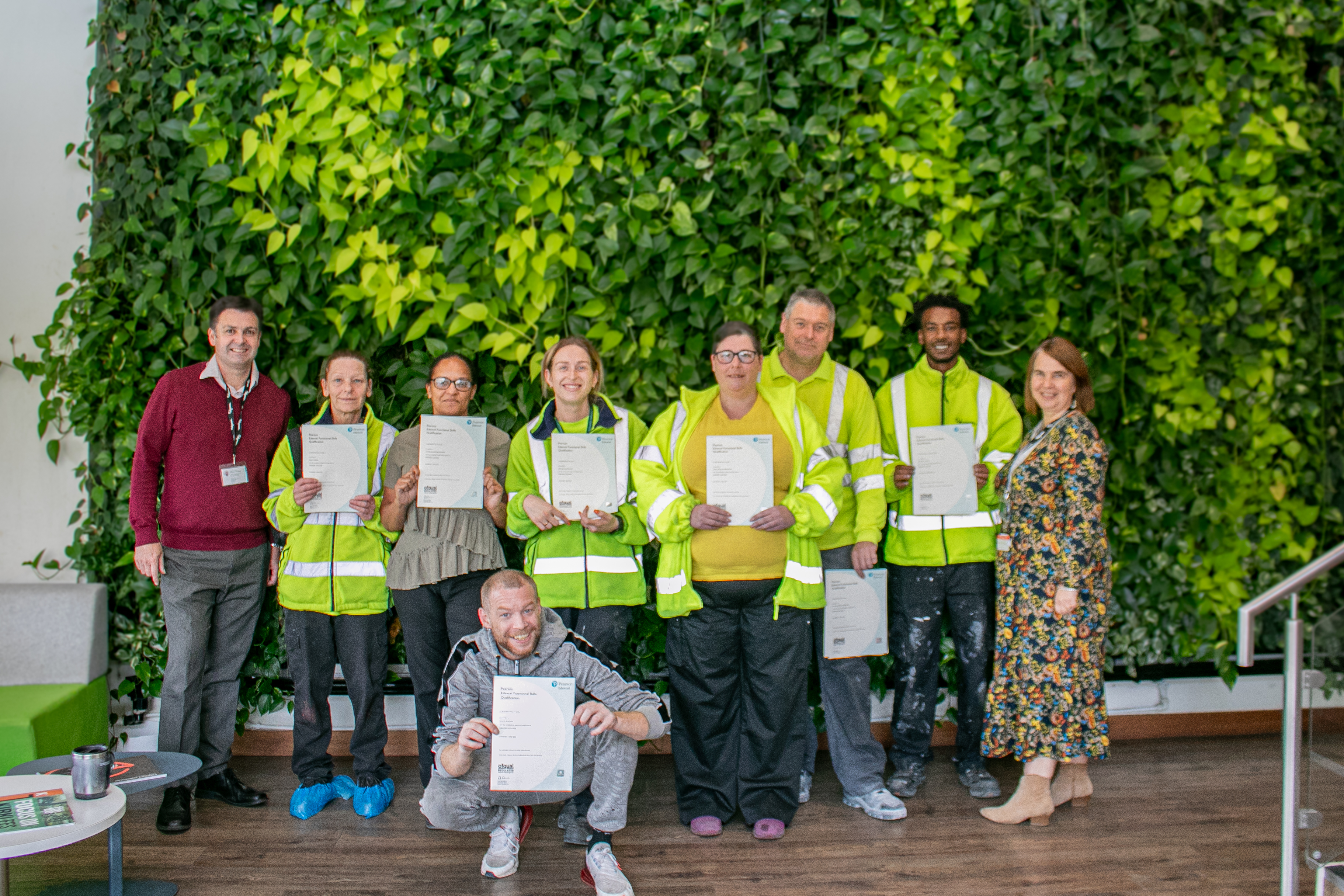 Polyseam employers pose with their functional skills certificates in front of a forest wall