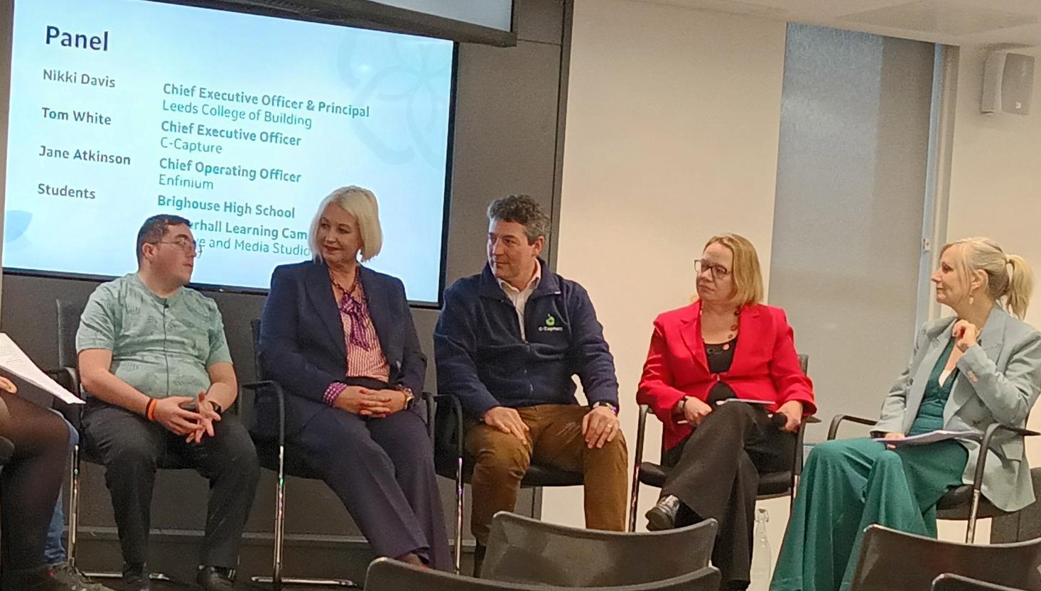 Five people from the Green Taskforce sit on stage, in front of a screen that has panel names on, discussing