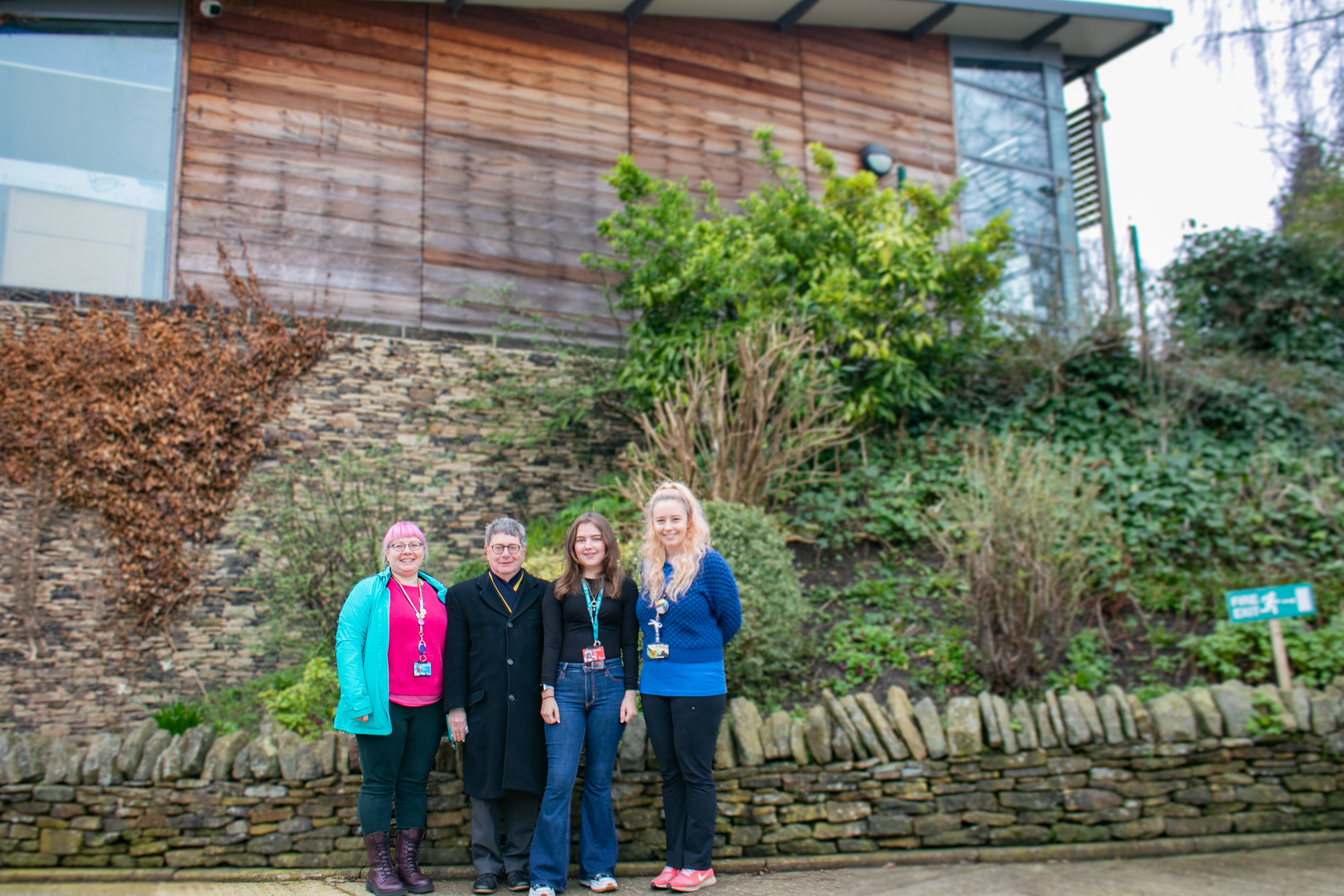 Jax Lovelock, Malcolm Parkinson, Megan Koolaji and Rebecca Easterbook stand in front of rock wall with leaves at Taylor Hill Animal Centre