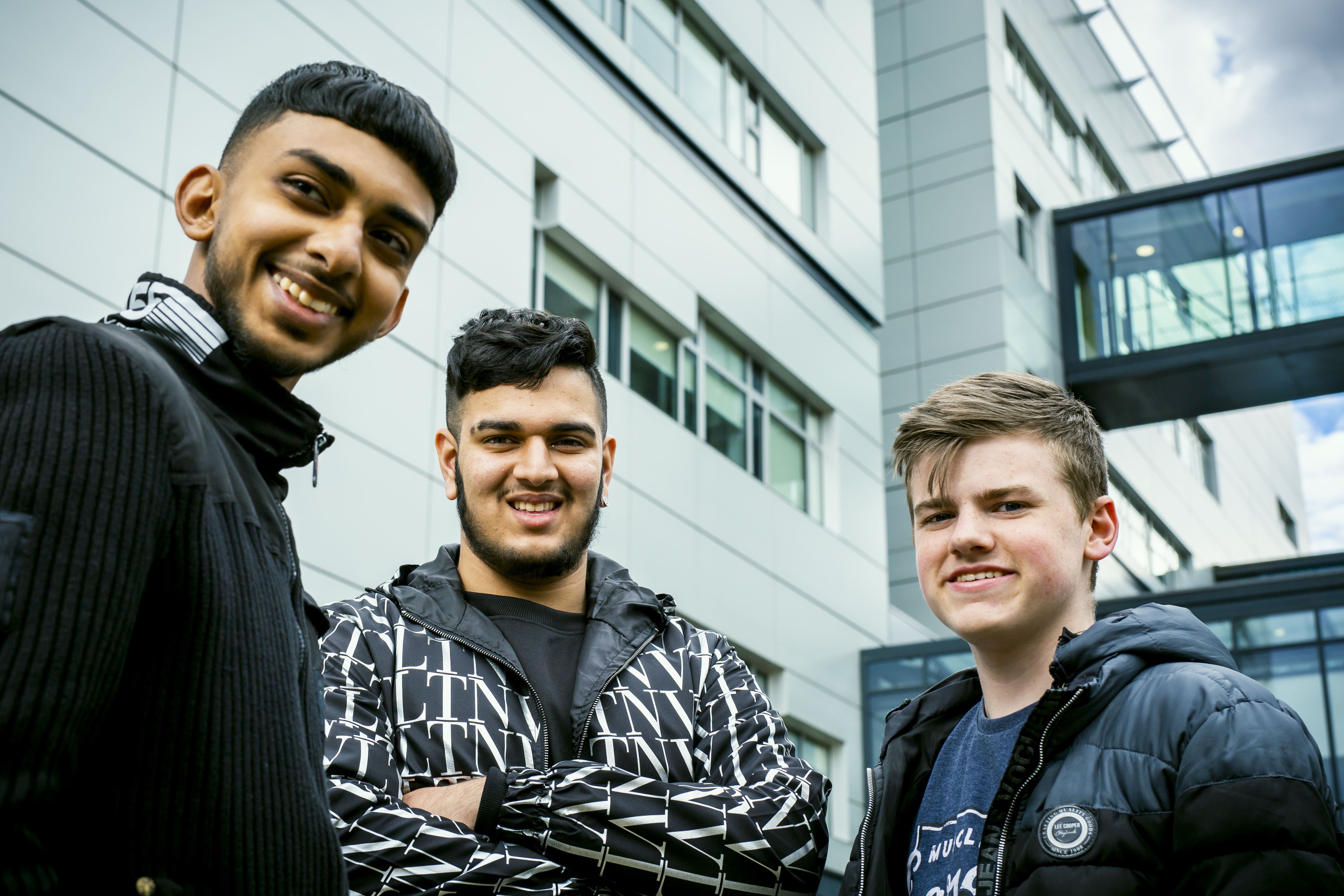 Three male students stand outside Huddersfield Centre