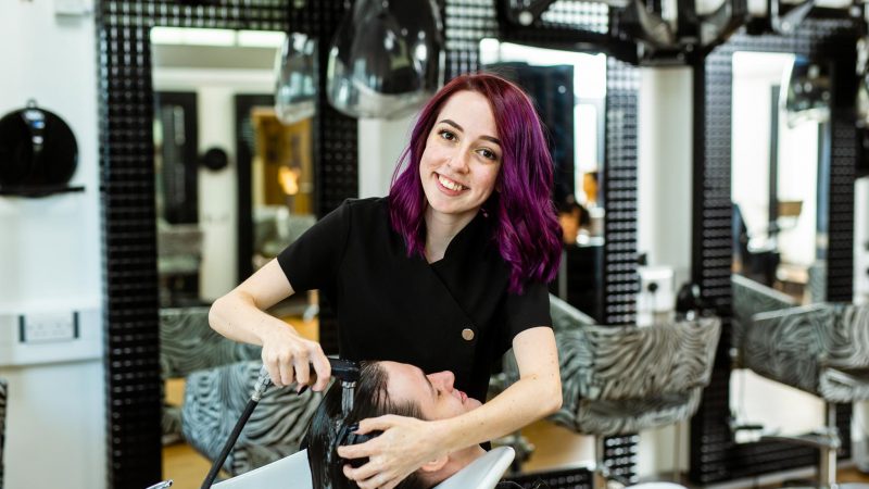 Barbering Student Washing Client's Hair Whilst Looking at the Camera