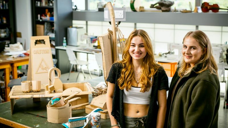 Art and Design Students Standing Next to Crafted Cardboard Projects