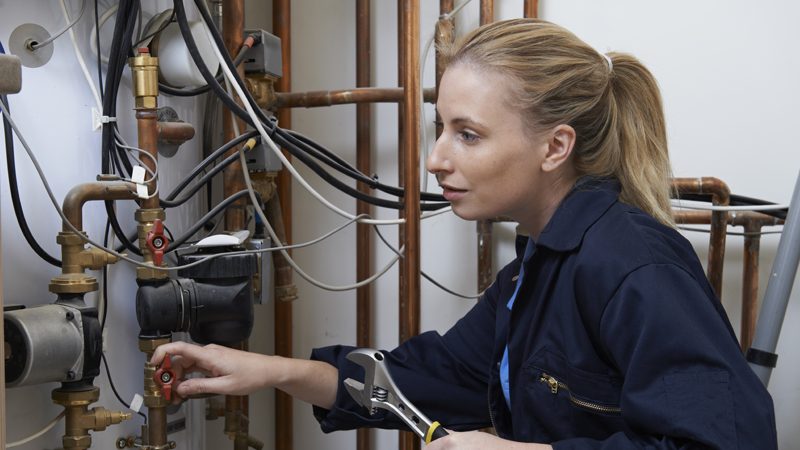 A young female plumb refitting a boiler