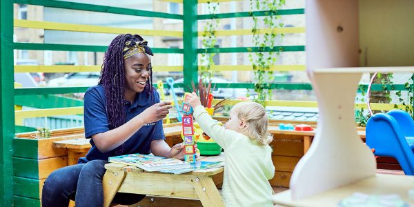 A young nursery teacher playing with a small toddler