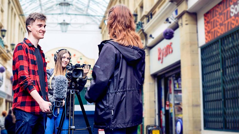 A film crew and interviewer speaking to a woman inside a converted old traditional victorian building