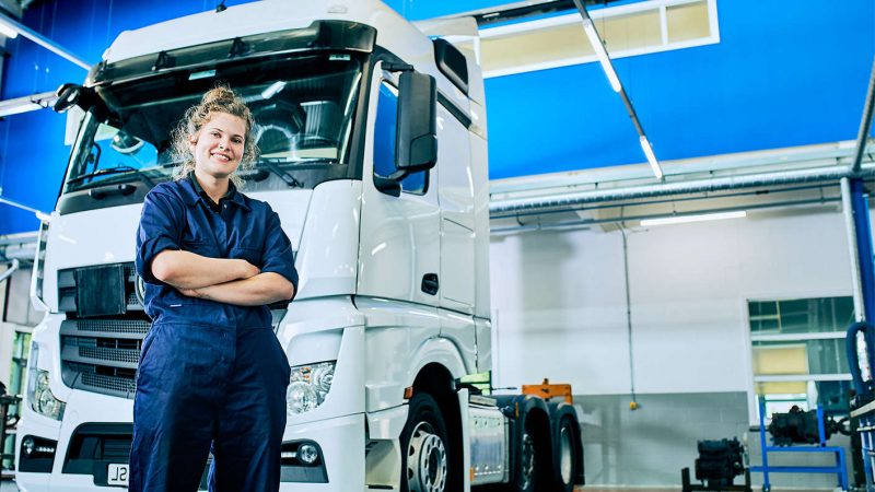 a female kirklees student wearing blue overalls stood in front of a truck