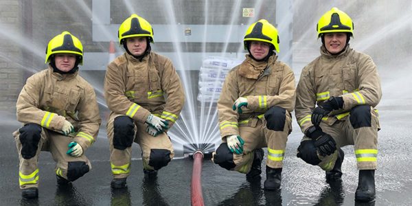 a group of firemen stood next to a hose